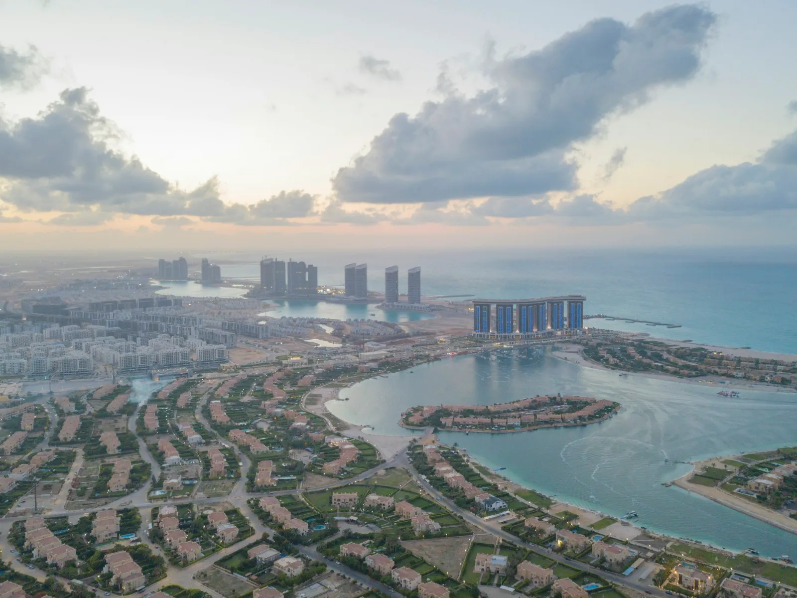 Aerial view of the Mediterranean coast at El Alamein — lagoons, resort homes and high-rise towers on the horizon